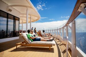 a few people relaxing looking out at the water on a cruise ship