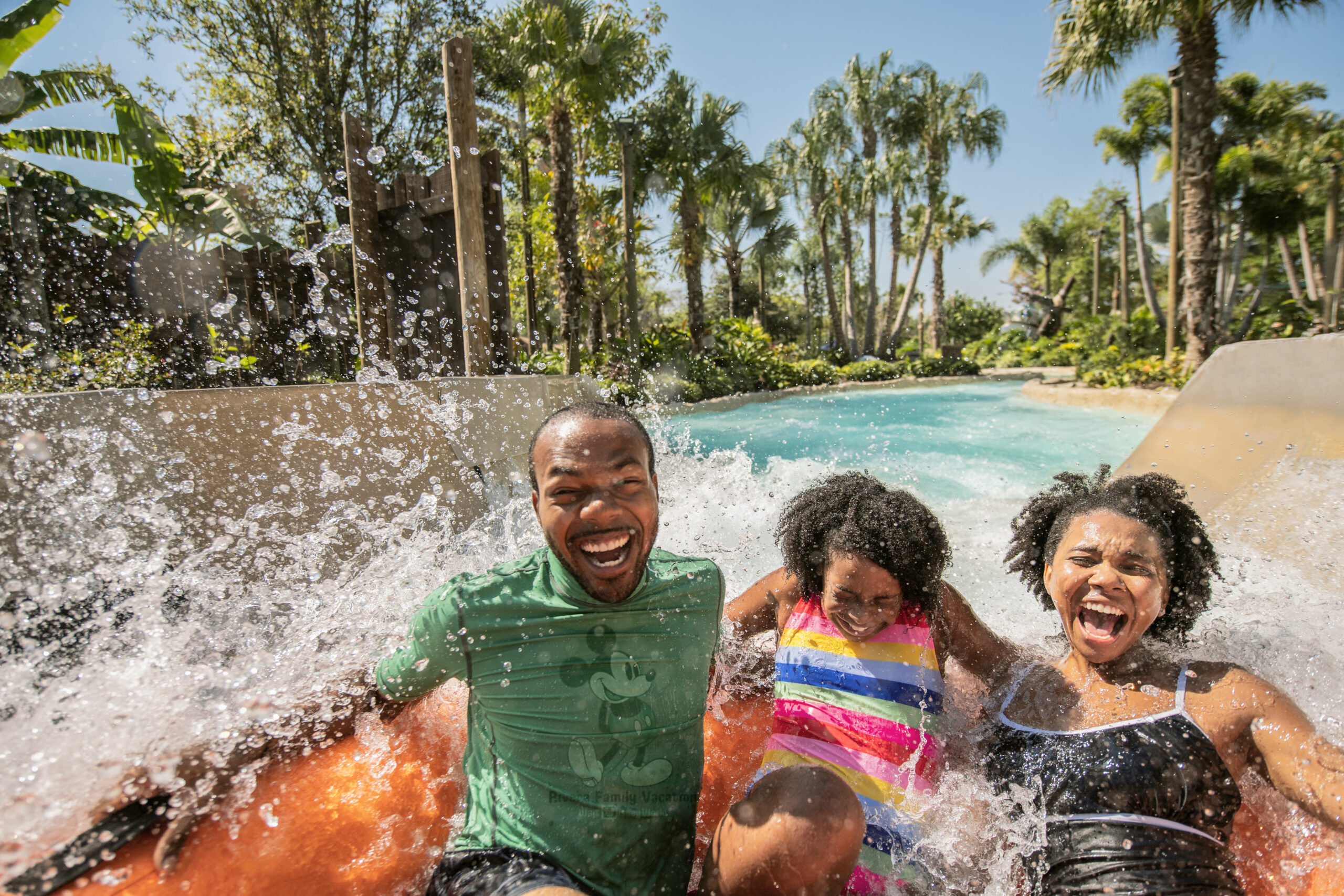 a family of three on a water raft getting soaked at Disney's Typhoon Lagoon Water Park