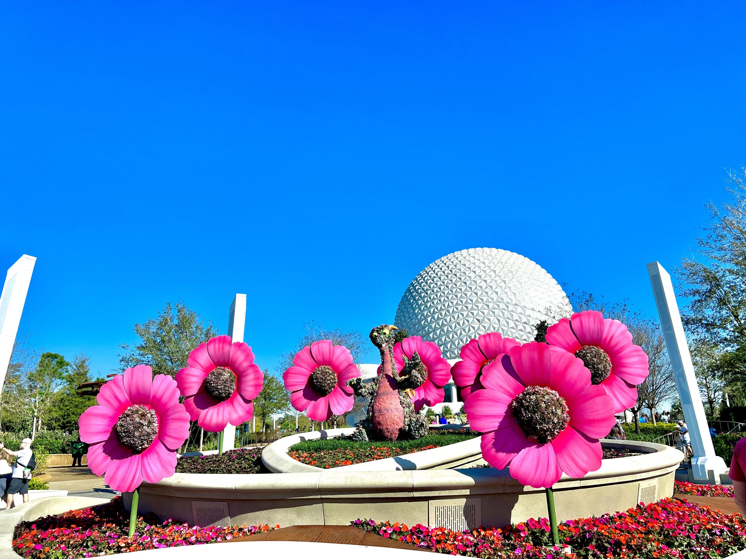 figment topiary with large flowers in front of spaceship earth