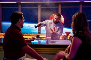 two guests and a bartender showing off a drink at hyperspace lounge on disney wish